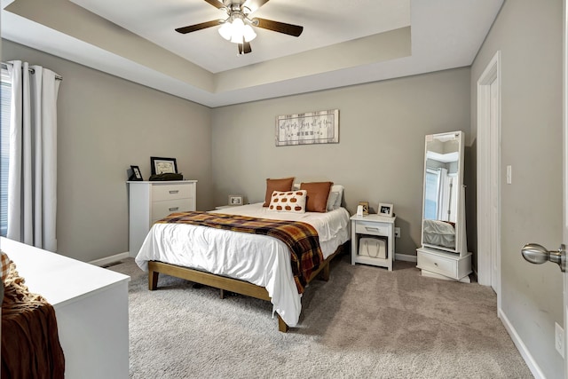 bedroom featuring ceiling fan, a raised ceiling, and carpet