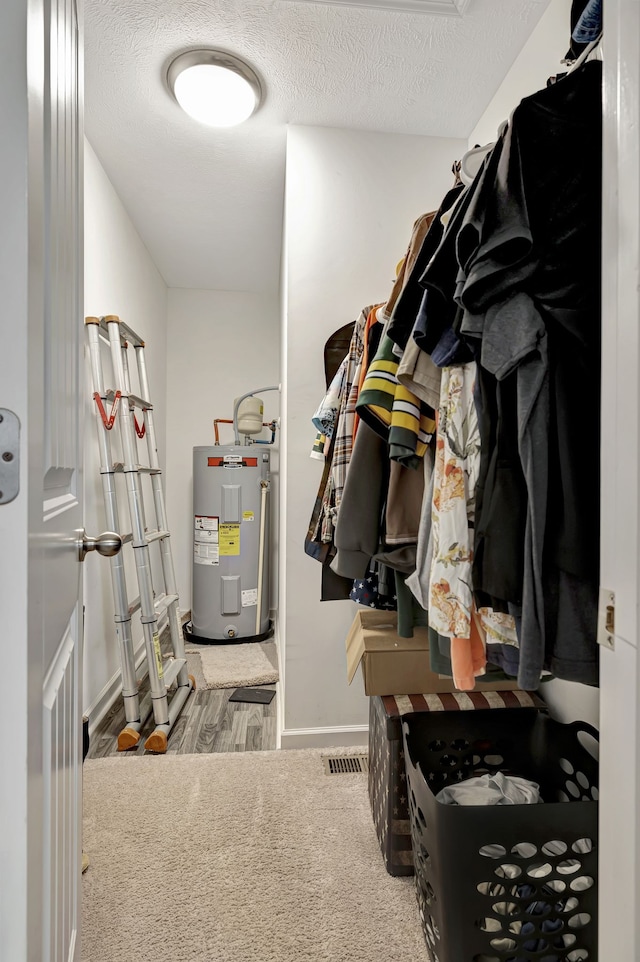 walk in closet featuring water heater and carpet