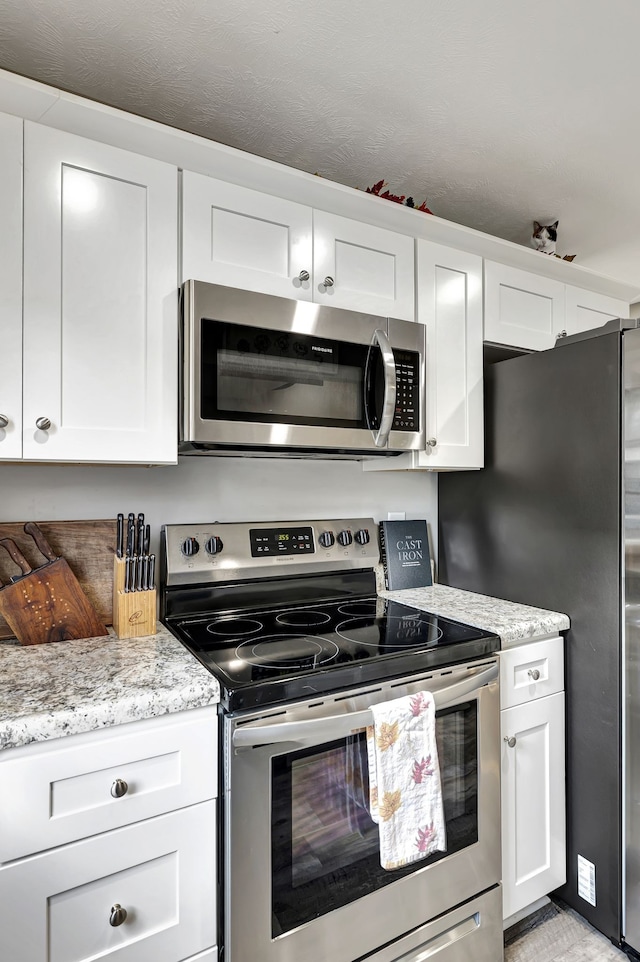 kitchen featuring white cabinets, light stone countertops, and stainless steel appliances