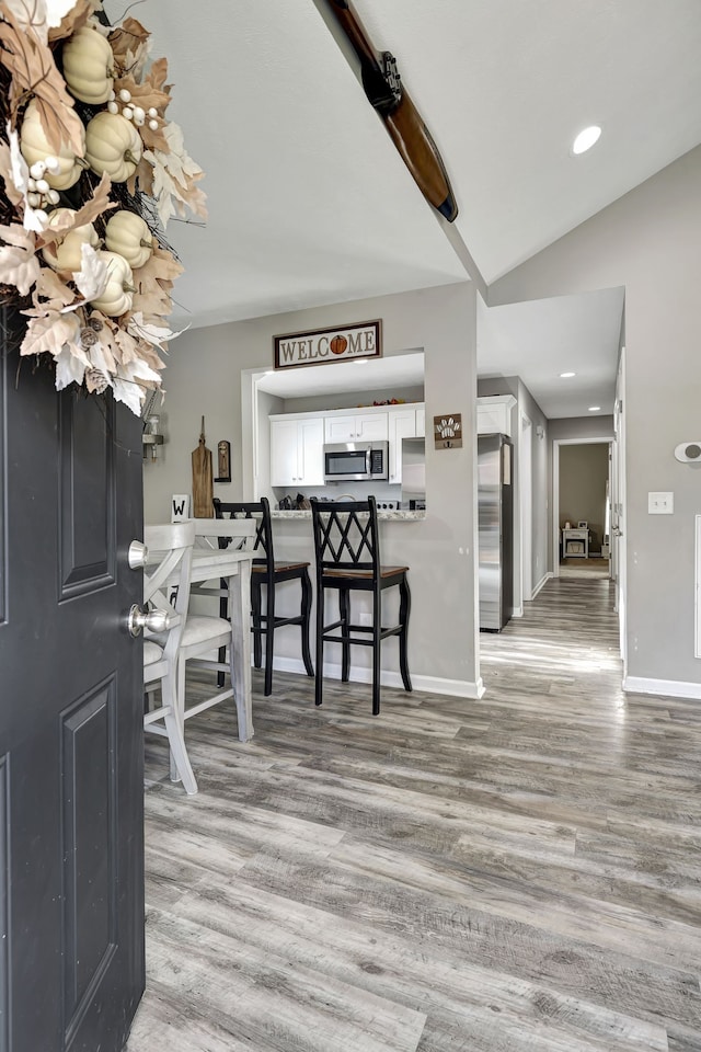 dining room with vaulted ceiling and light hardwood / wood-style flooring