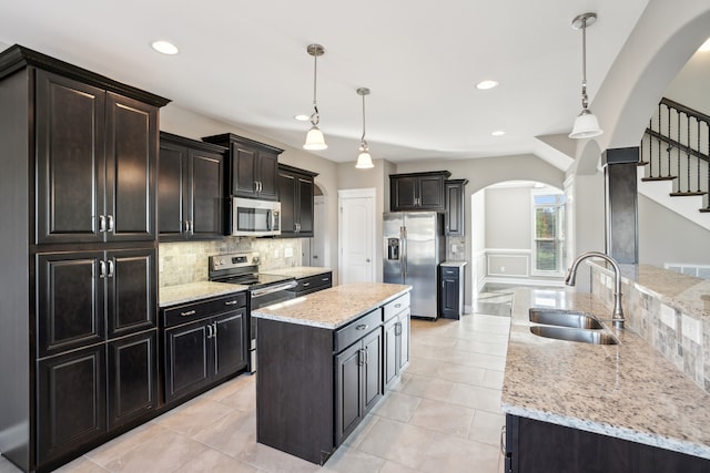 kitchen with appliances with stainless steel finishes, a center island, decorative light fixtures, and sink