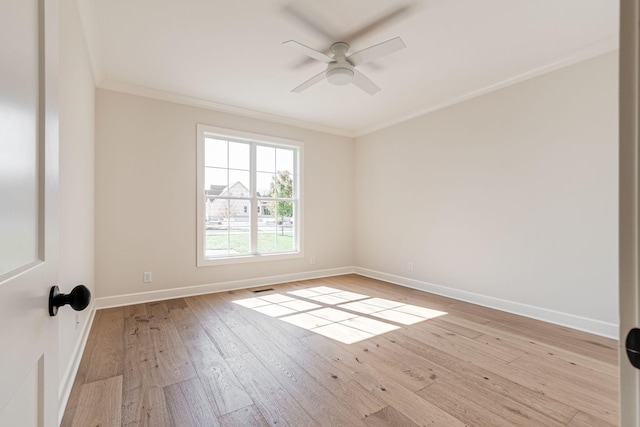 spare room with ceiling fan, visible vents, hardwood / wood-style flooring, baseboards, and ornamental molding
