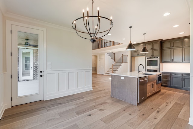 kitchen featuring pendant lighting, an island with sink, stainless steel appliances, and light wood-type flooring