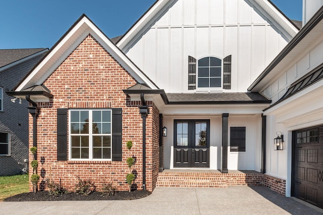 entrance to property featuring a shingled roof, board and batten siding, and brick siding