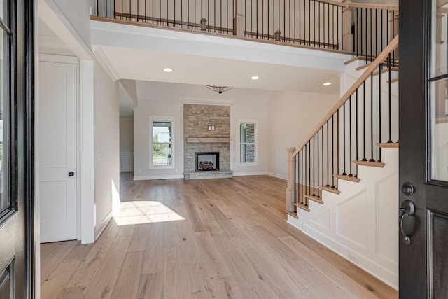 entryway with stairway, baseboards, light wood-type flooring, and a stone fireplace