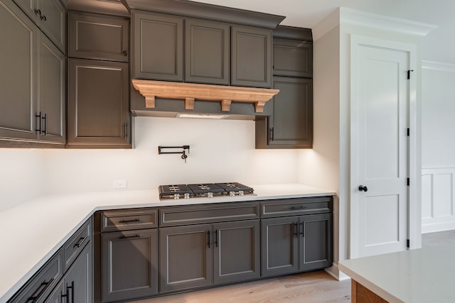 kitchen with ornamental molding, stainless steel gas stovetop, and light wood-type flooring