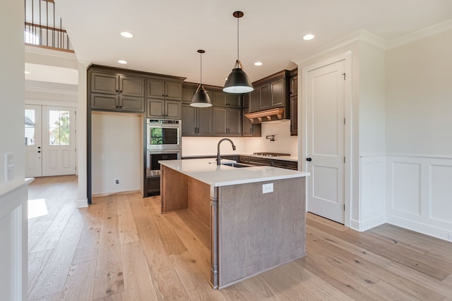 kitchen featuring dark brown cabinets, a center island with sink, sink, appliances with stainless steel finishes, and light hardwood / wood-style floors