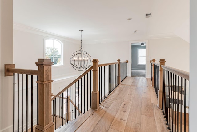 hall featuring an inviting chandelier, visible vents, light wood-style flooring, and an upstairs landing