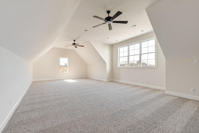 additional living space featuring light carpet, lofted ceiling, and visible vents