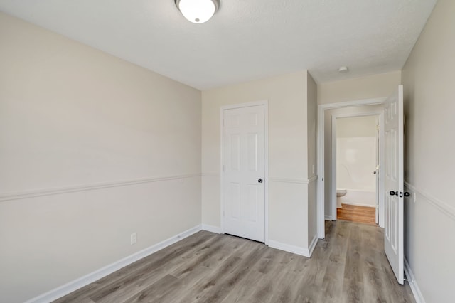 unfurnished bedroom with a closet, a textured ceiling, and light wood-type flooring