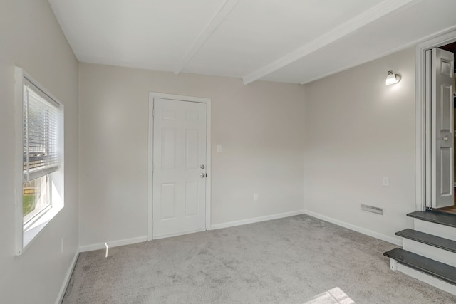 carpeted spare room with beam ceiling