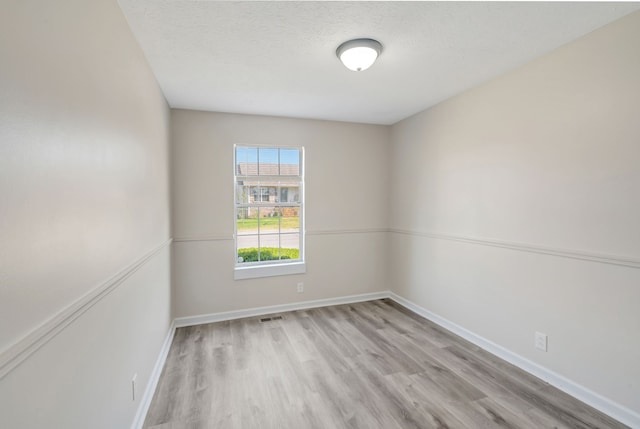 unfurnished room with a textured ceiling and light wood-type flooring