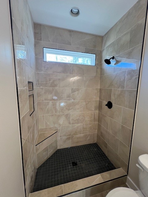 bathroom featuring toilet and a tile shower