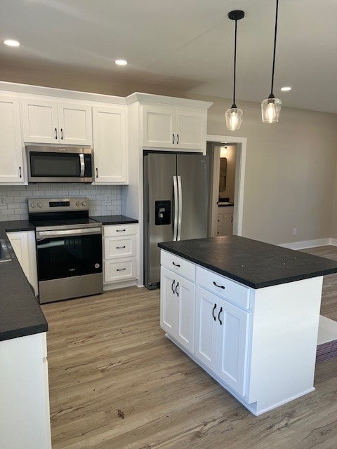 kitchen with white cabinets, stainless steel appliances, and hanging light fixtures