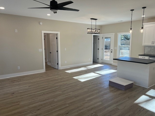 kitchen featuring pendant lighting, dark wood-type flooring, white cabinets, decorative backsplash, and ceiling fan