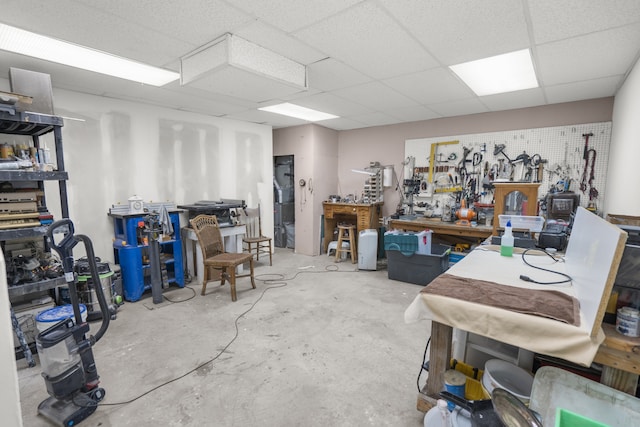 misc room featuring a workshop area, a drop ceiling, and concrete flooring