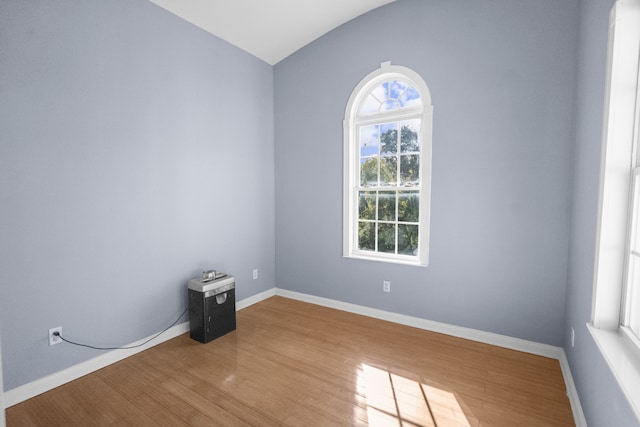 unfurnished room with hardwood / wood-style flooring and lofted ceiling