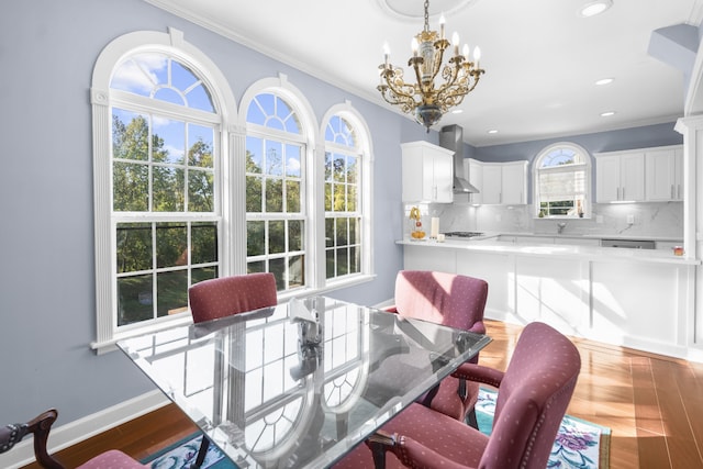 dining space featuring ornamental molding, sink, wood-type flooring, and an inviting chandelier