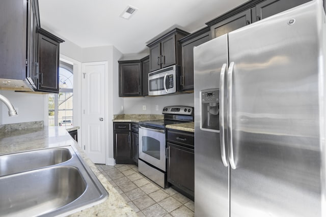 kitchen featuring light stone countertops, sink, appliances with stainless steel finishes, and light tile patterned flooring