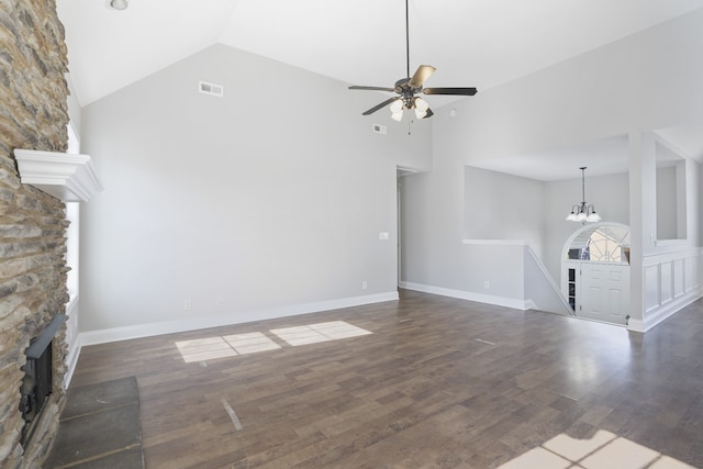 unfurnished living room featuring ceiling fan with notable chandelier, high vaulted ceiling, dark hardwood / wood-style floors, and a stone fireplace