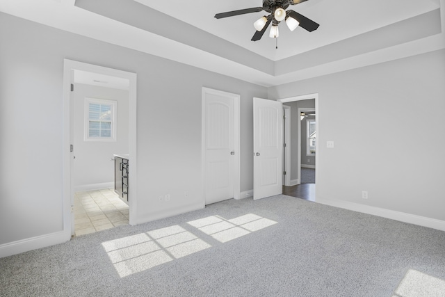 unfurnished bedroom with light carpet, connected bathroom, and ceiling fan