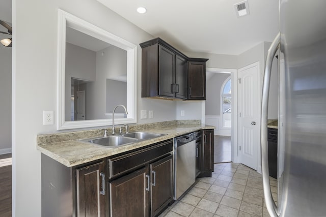 kitchen featuring light tile patterned flooring, dark brown cabinetry, stainless steel appliances, and sink