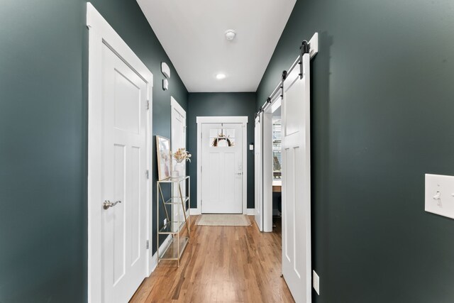 hall featuring a barn door and light hardwood / wood-style flooring