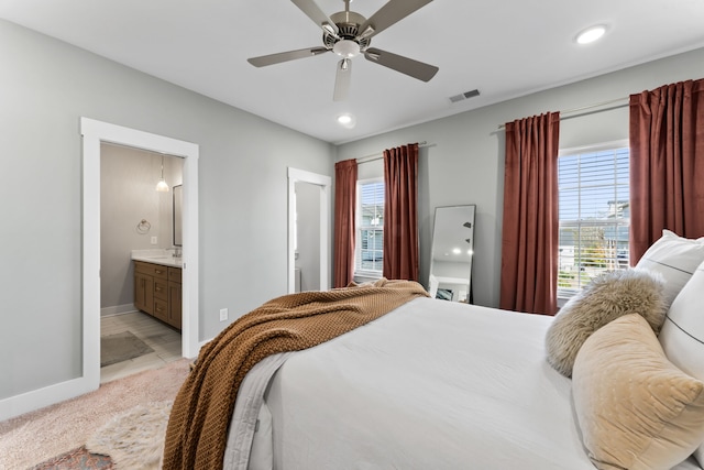 bedroom featuring ensuite bath, ceiling fan, and multiple windows