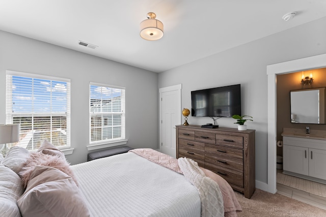 bedroom with light colored carpet and ensuite bath