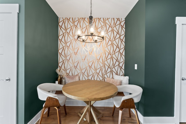 dining area with breakfast area, wood-type flooring, and an inviting chandelier