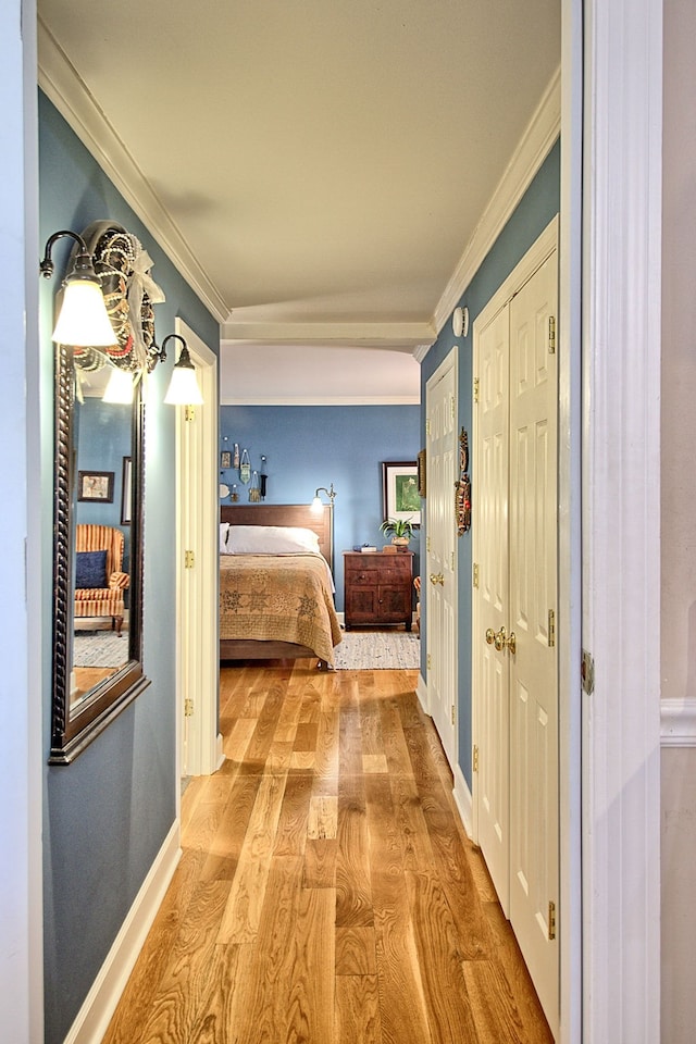 unfurnished bedroom featuring crown molding, multiple closets, and light hardwood / wood-style flooring