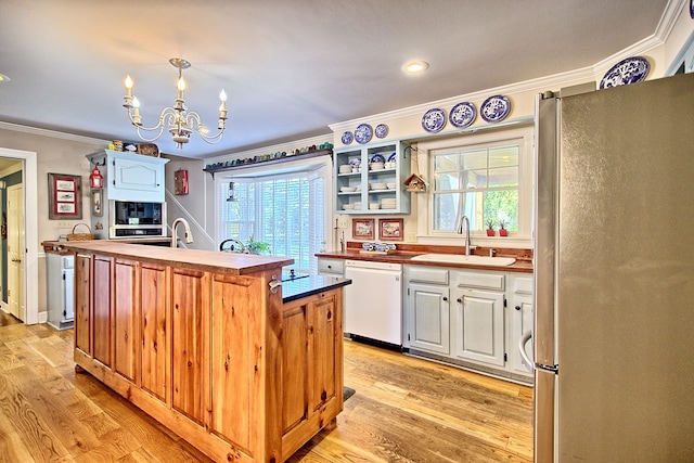 kitchen featuring stainless steel fridge, white cabinets, a center island with sink, white dishwasher, and sink