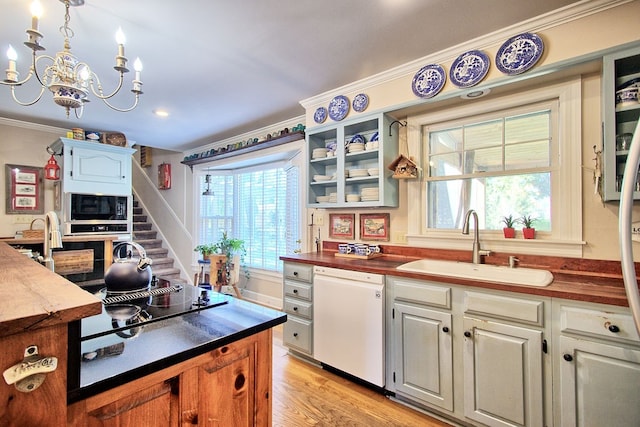 kitchen featuring black appliances, sink, light wood-type flooring, butcher block countertops, and white cabinetry