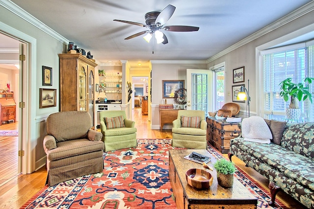 living room featuring light hardwood / wood-style floors, ornamental molding, and ceiling fan