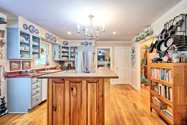 kitchen featuring hanging light fixtures, crown molding, stainless steel refrigerator, light hardwood / wood-style flooring, and an inviting chandelier