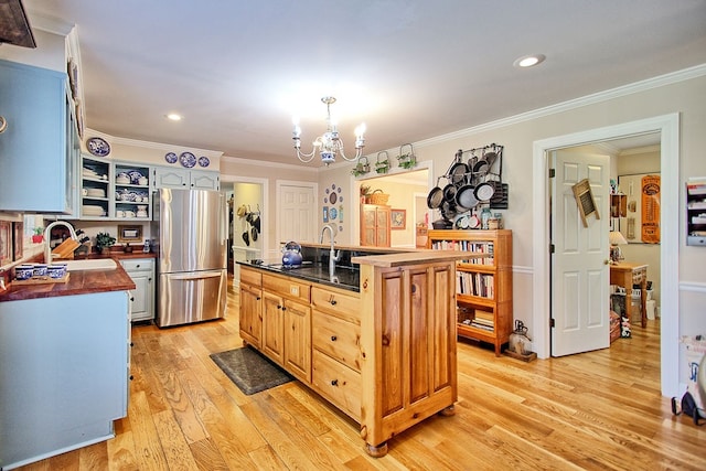 kitchen with a center island, ornamental molding, light hardwood / wood-style floors, stainless steel refrigerator, and a chandelier