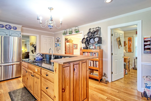 kitchen with stainless steel fridge, ornamental molding, light hardwood / wood-style flooring, a chandelier, and a center island with sink