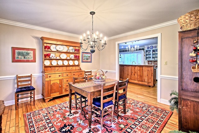 dining room with light hardwood / wood-style floors, ornamental molding, and a chandelier