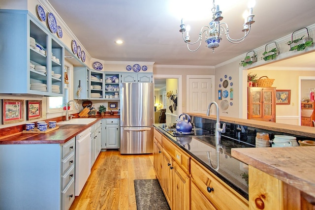 kitchen featuring stainless steel fridge, an inviting chandelier, light wood-type flooring, ornamental molding, and sink