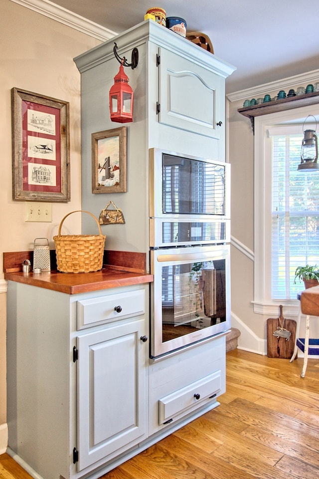 interior space featuring white cabinetry, ornamental molding, and light wood-type flooring