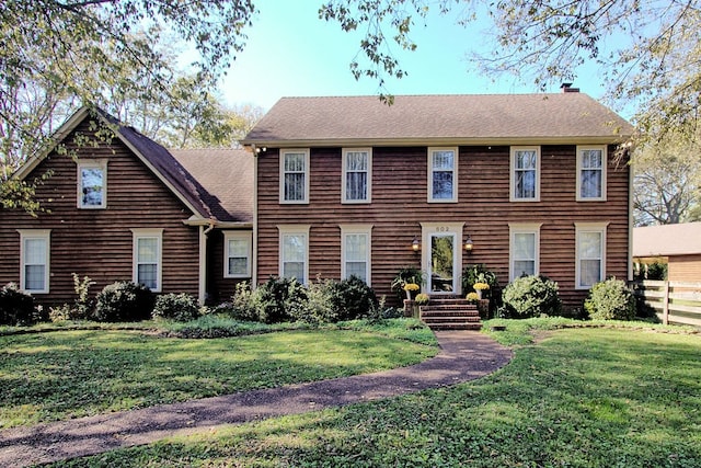 colonial-style house featuring a front yard