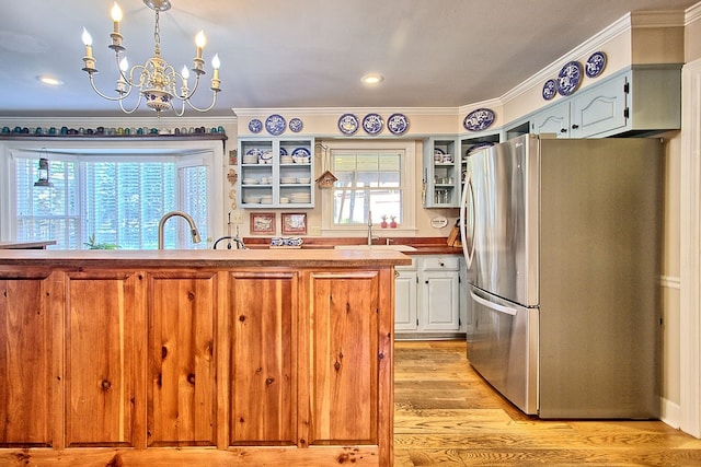 kitchen featuring ornamental molding, light hardwood / wood-style flooring, stainless steel fridge, and plenty of natural light