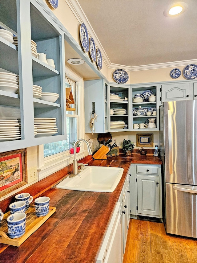 kitchen with light hardwood / wood-style flooring, sink, crown molding, butcher block countertops, and stainless steel refrigerator