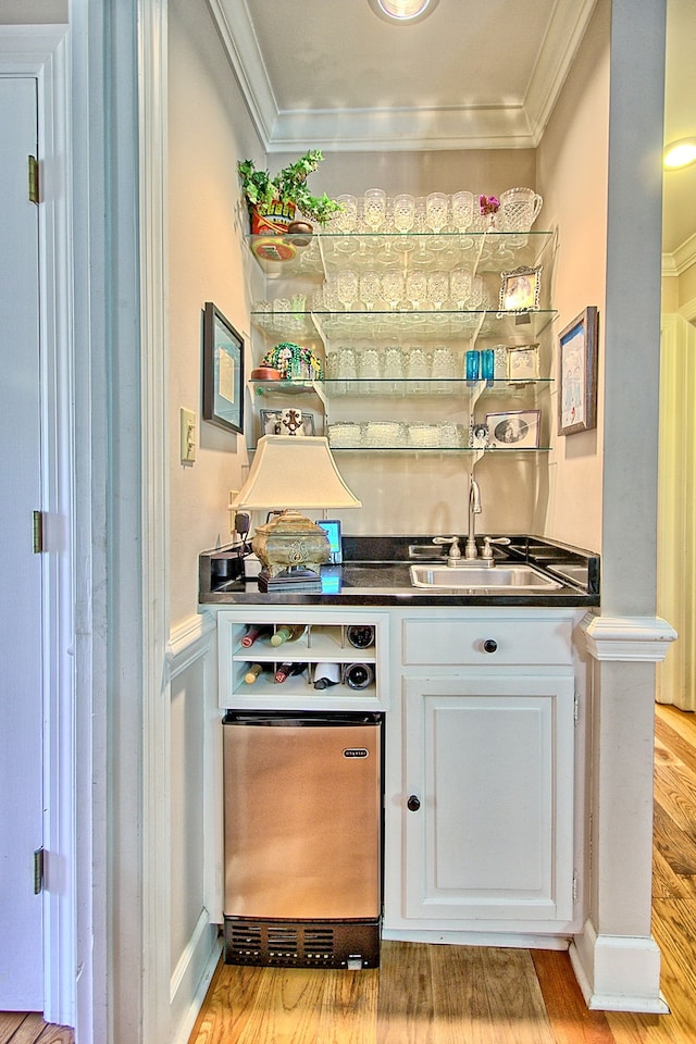 bar with ornamental molding, sink, white cabinets, and light hardwood / wood-style floors