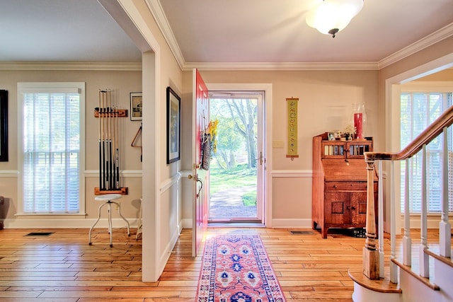 foyer featuring ornamental molding and light hardwood / wood-style flooring