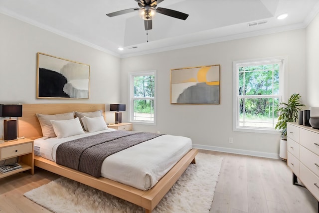 bedroom with a tray ceiling, ceiling fan, crown molding, and light hardwood / wood-style floors