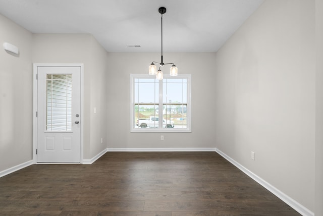 unfurnished dining area featuring dark wood-type flooring and a notable chandelier