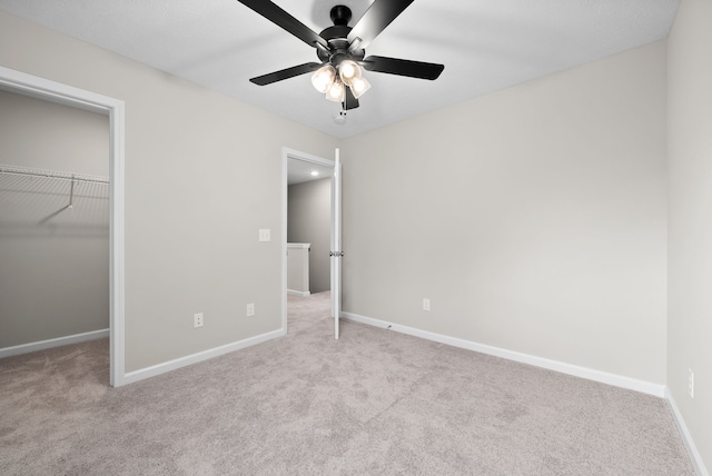 unfurnished bedroom featuring ceiling fan, a walk in closet, light carpet, and a closet