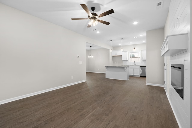 unfurnished living room with ceiling fan, sink, and dark wood-type flooring