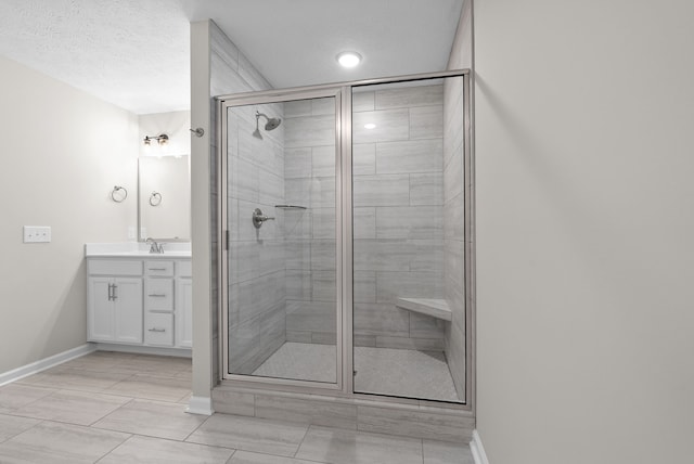 bathroom featuring a textured ceiling, vanity, and a shower with door